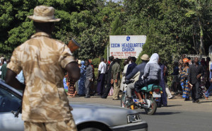 A soldier stands guard as people walk past a signboard of a church along a road in Nigeria's central city of Jos