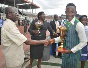 Governor Adams Oshiomhole of Edo State presents the 1st prize trophy to a student of New Covenant Christian College, Benin City at the March pass to mark Nigeria's 55th Independence Anniversary, Benin City, on Thursday.