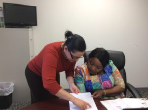 Apostle Naomi Osagiede, seated and reviewing a document with a staff member.