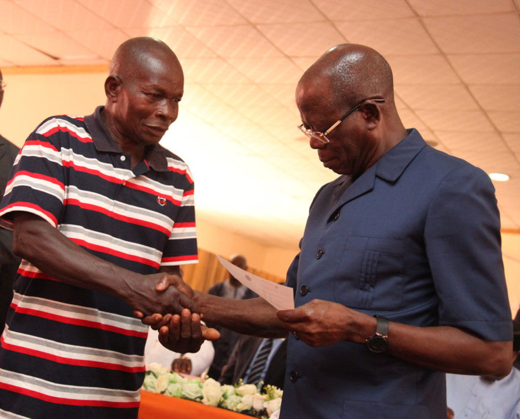 Mr. Joseph Igunbor, of Iguomokhua Imade Yam Growers receives a cheque from Governor Adams Oshiomhole on behalf of the group at the disbursement of N2 billion Micro, Small and Medium Enterprise Development Fund (MSMEDF),  by the state Government, on Monday.