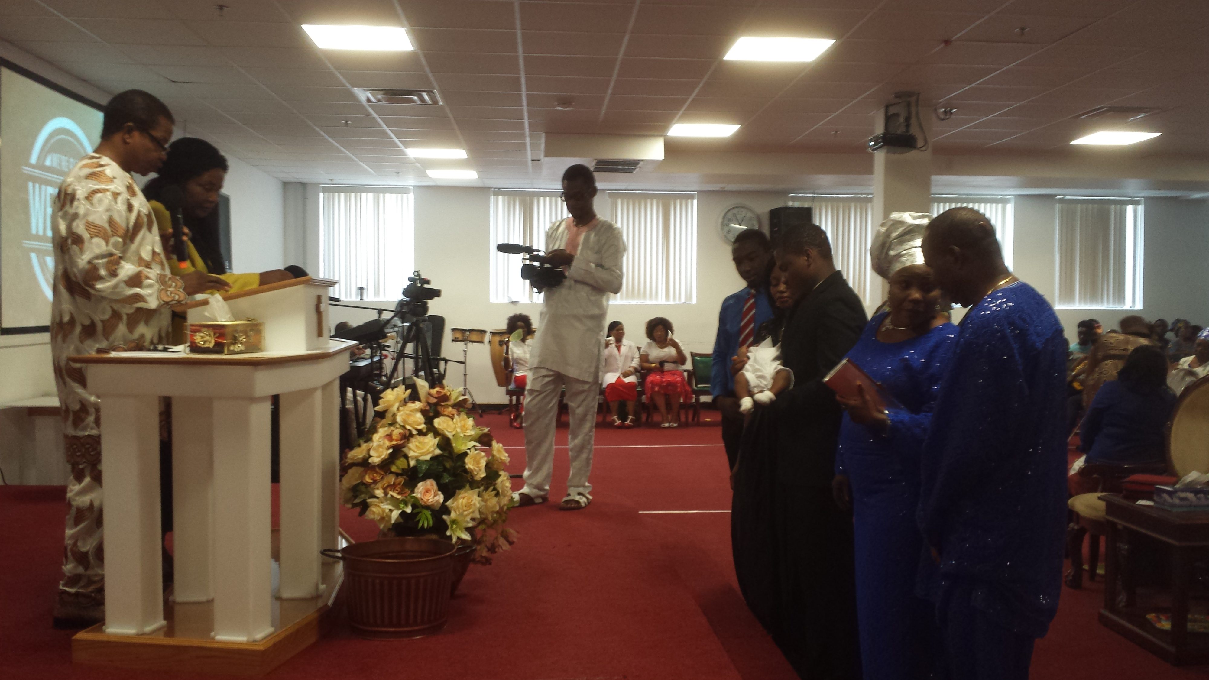 Pastor John and Bridget Aikhionbare (left) at the altar, blessing thier new-born grandchild during the dedication of his life to God.